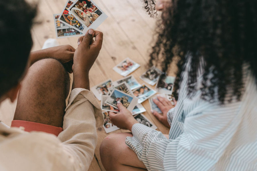 A couple looking through printed photographs together while choosing meaningful paper memories to keep.