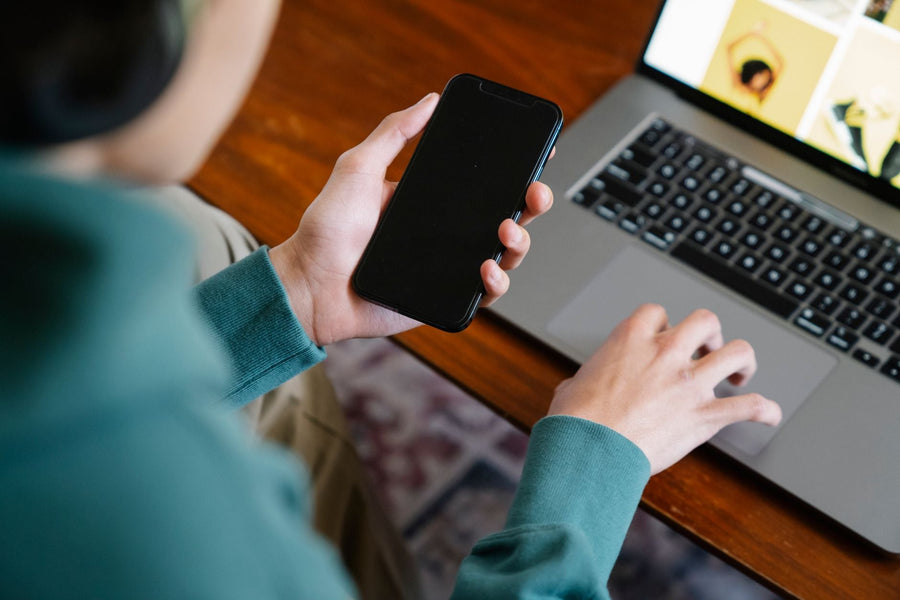A person using a smartphone beside a laptop while organizing an important recording for safekeeping.